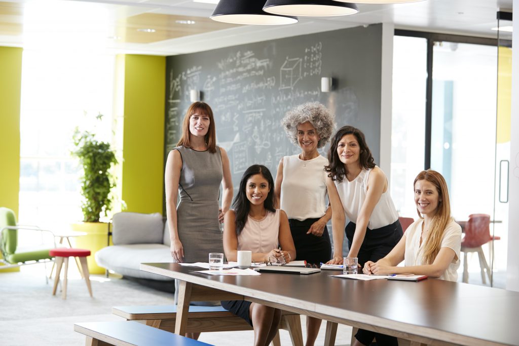 A group of women gathered around a table in a bright office